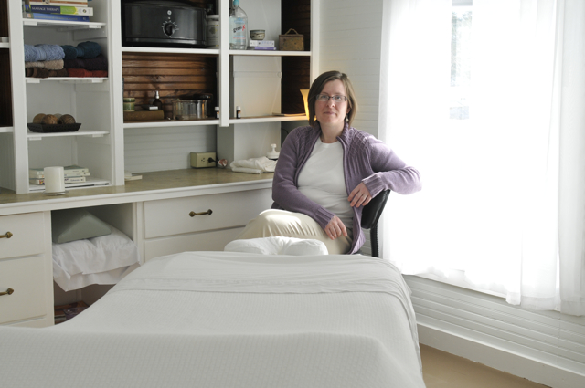 Emily Bilodeau, licensed massage therapist, seated near the treatment table in her office