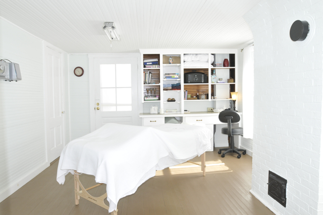 a massage table with white linens set up in the treatment space at Serenity Holistic Massage